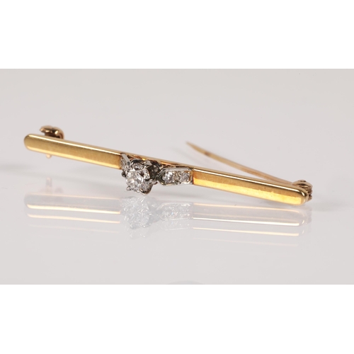 58 - Yellow metal bar brooch set with a diamond flanked by four smaller diamonds, 4.5g