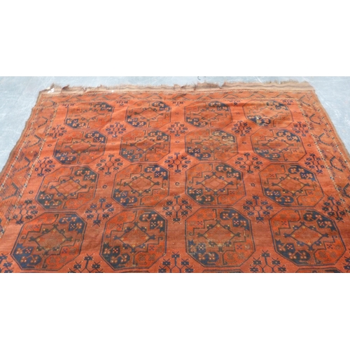 327 - Afghan-style Belouch carpet with rows of geometric medallions on a red ground.