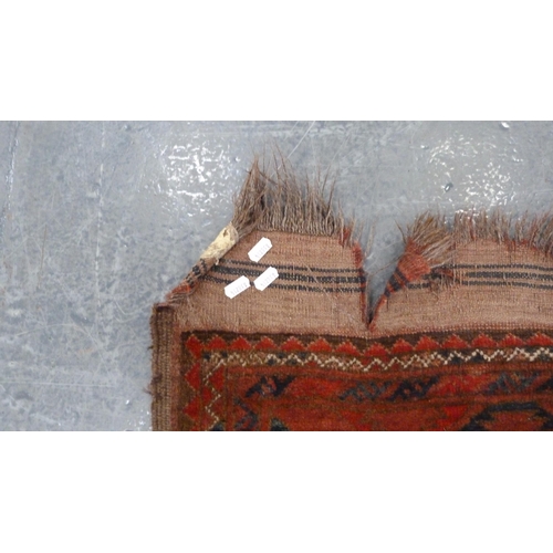 327 - Afghan-style Belouch carpet with rows of geometric medallions on a red ground.