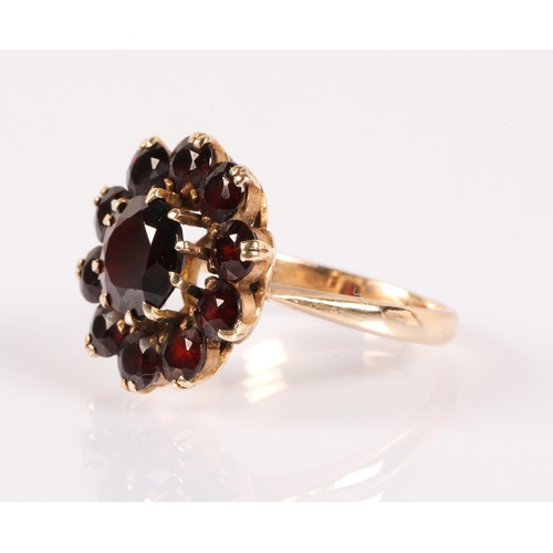 61 - 9ct gold ring set with deep red garnets set in a flower design, ring size P, 4.8g