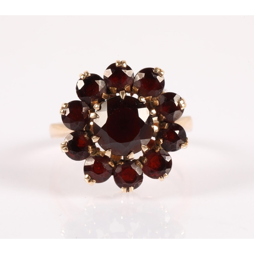 61 - 9ct gold ring set with deep red garnets set in a flower design, ring size P, 4.8g