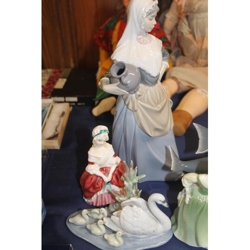 33 - Nao figurine of a washerwoman, a Lladro dolphin model and Royal Doulton figures.