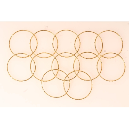 141 - Set of twelve yellow metal bangles, of plain form with patterned edges.