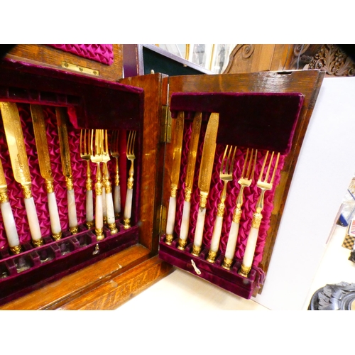 76 - Set of ornate gilt silver plated fruit knives and forks, adapted into an oak case.