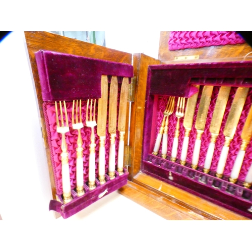 76 - Set of ornate gilt silver plated fruit knives and forks, adapted into an oak case.