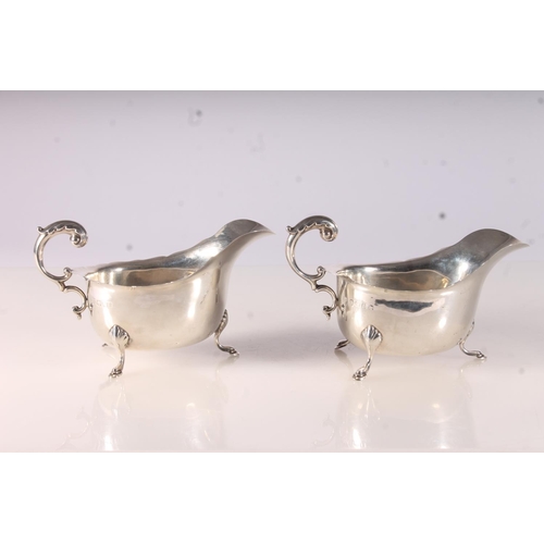 40 - Two Geo. V silver cream jugs, with scalloped edges and acanthus scroll handles on three shell and pa... 