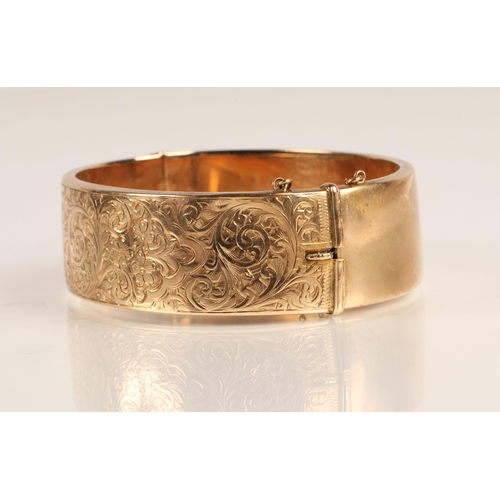 73 - Ladies 9ct yellow gold broad hinged bangle with engraved detail, weight 23.8g
