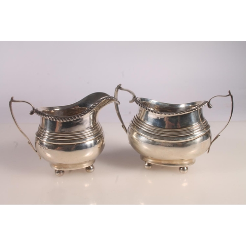 20 - Geo. V silver three piece tea set, the teapot with scrolled ebonised handle, gadrooned rim over a st... 