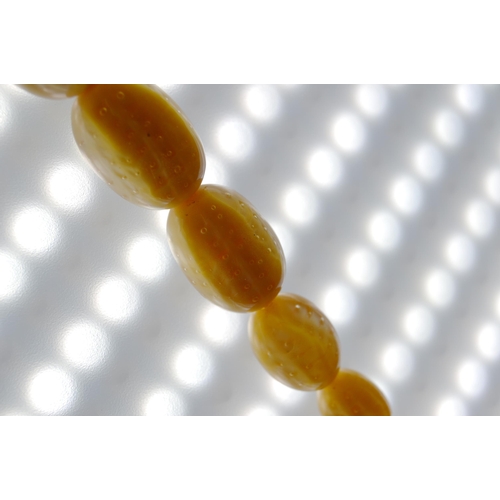 65 - String of Baltic translucent amber beads, c. early 20th century, comprising sixty-two graduated oval... 
