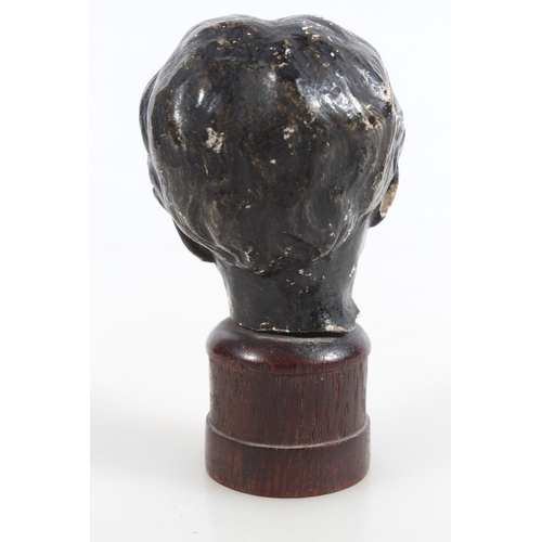 48 - Antique bronze effect on plaster statue bust of a young boy, raised on wooden base, 10.5cm tall.