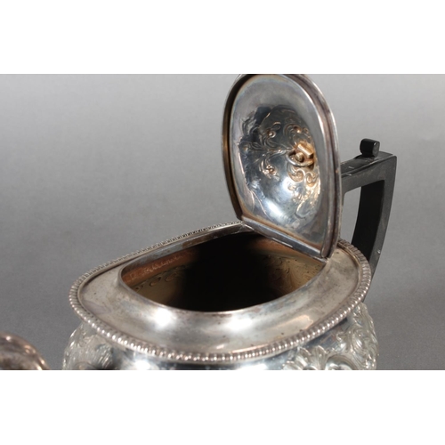 19 - Victorian silver teapot with heavily foliate decorated body and ebonised handle raised on ball suppo... 
