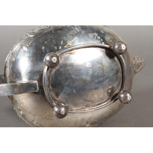 19 - Victorian silver teapot with heavily foliate decorated body and ebonised handle raised on ball suppo... 