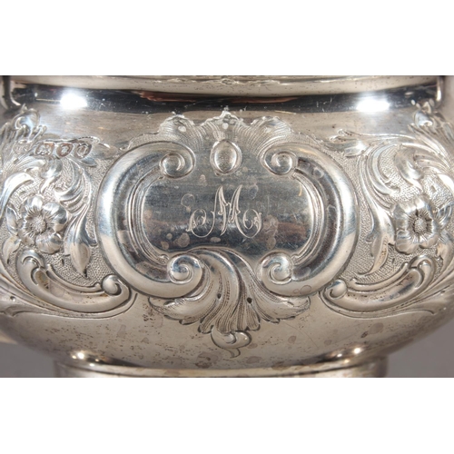 19 - Victorian silver teapot with heavily foliate decorated body and ebonised handle raised on ball suppo... 