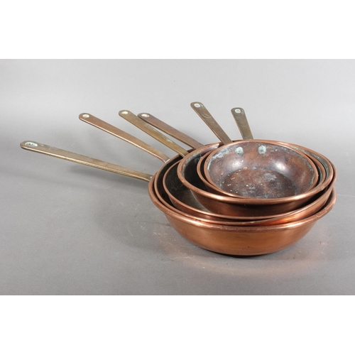 Six graduated copper cooking pans.