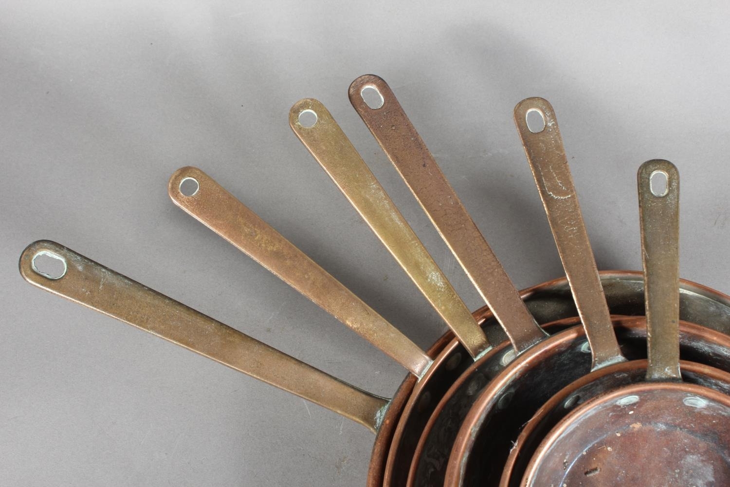 Six graduated copper cooking pans.
