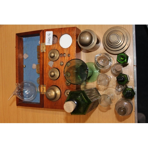 260G - Apothecary items to include glass bottles, glass measure, cased set of weights, nesting weights, eye... 