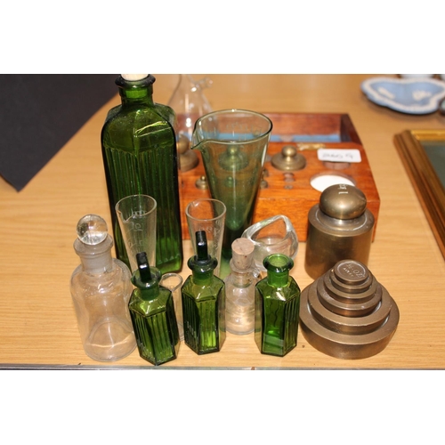 260G - Apothecary items to include glass bottles, glass measure, cased set of weights, nesting weights, eye... 