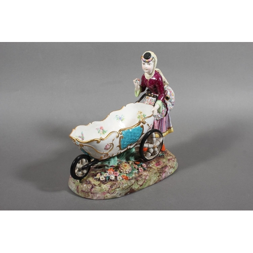213 - Continental novelty porcelain cream boat in the form of a female flower seller pushing a three wheel... 