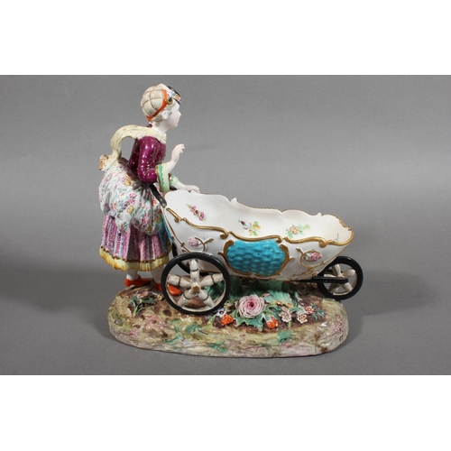 213 - Continental novelty porcelain cream boat in the form of a female flower seller pushing a three wheel... 