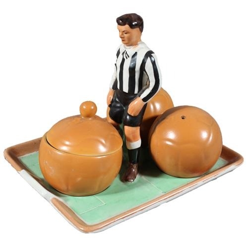 Rare Art Deco Carlton Ware novelty cruet set modelled as a footballer wearing black and white stripes in the manner of Newcastle United, three footballs as the lift-out cruets, registration number '749837', registered in the year 1929, 13cm long.