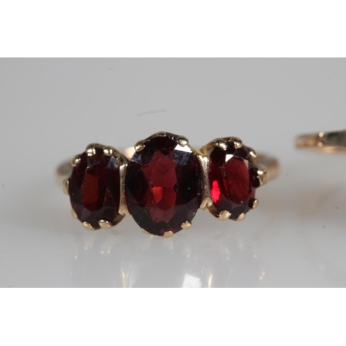478 - 9ct yellow gold garnet three stone set ring and another, 4.7g.