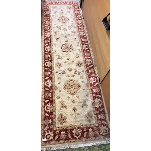 513 - Cream and red ground hall runner with floral decoration.