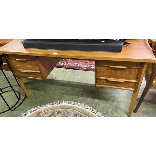 520 - Teak kneehole four drawer desk on turner supports.