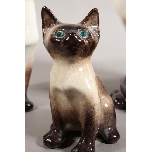 14 - Three Winstanley pottery Siamese cats with blue eyes, largest 31cm high.