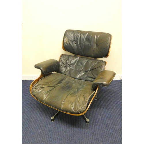 409 - Charles and Ray Eames chair and a footstool upholstered in black leather.