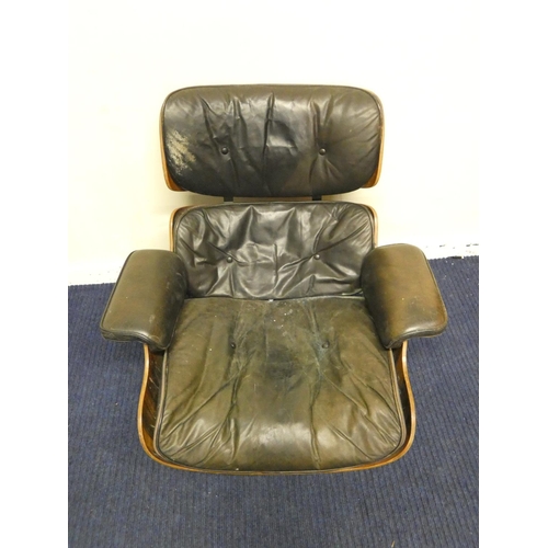 409 - Charles and Ray Eames chair and a footstool upholstered in black leather.