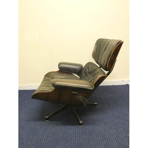 409 - Charles and Ray Eames chair and a footstool upholstered in black leather.