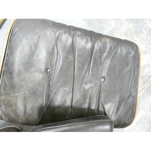 409 - Charles and Ray Eames chair and a footstool upholstered in black leather.