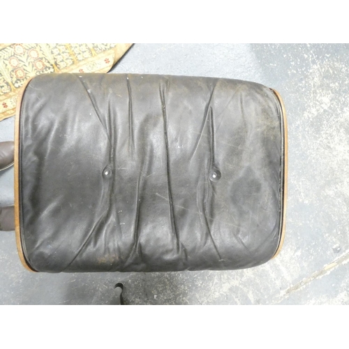 409 - Charles and Ray Eames chair and a footstool upholstered in black leather.