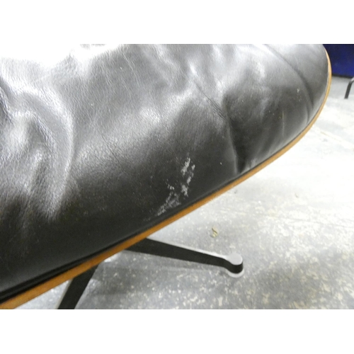 409 - Charles and Ray Eames chair and a footstool upholstered in black leather.