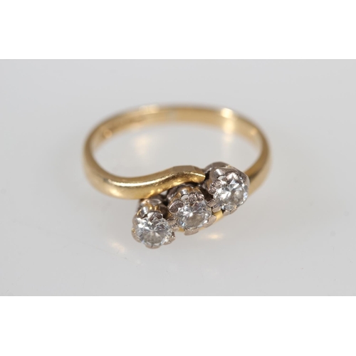 176 - 18ct yellow gold diamond three stone crossover ring, the diamonds and claw setting, size K, 3.4g.