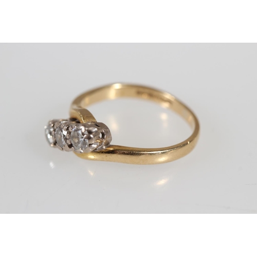 176 - 18ct yellow gold diamond three stone crossover ring, the diamonds and claw setting, size K, 3.4g.