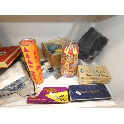110 - Three shelves of sundries to include boxed model vehicles, games, reels of thread and ornaments, sof... 