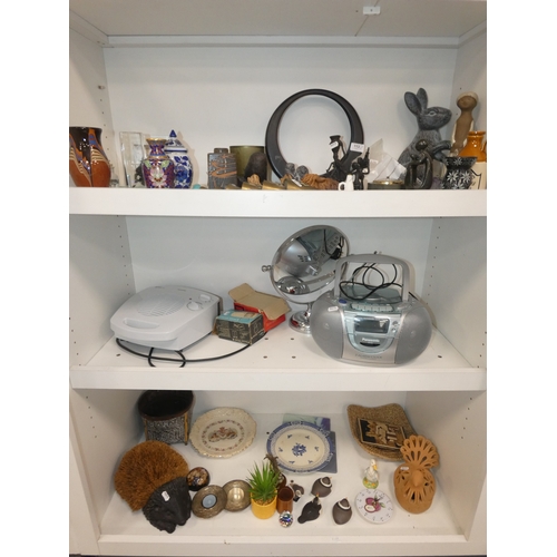 113 - Three shelves of sundries to include Panasonic 2-alarm/clock and cd player, fan heater, ornaments to... 