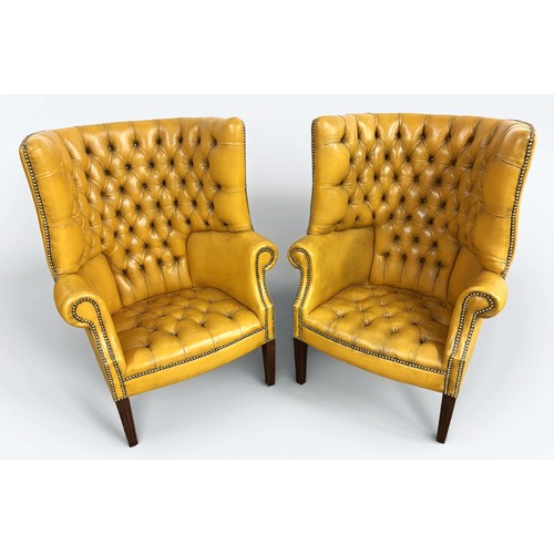 324 - Pair of chesterfield wingback chairs upholstered in mustard yellow leather. 113cm high, 80cm wide.