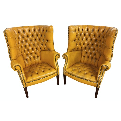 324 - Pair of chesterfield wingback chairs upholstered in mustard yellow leather. 113cm high, 80cm wide.