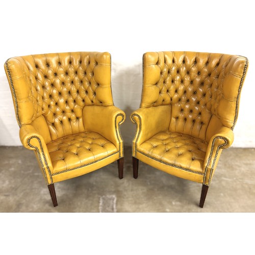 324 - Pair of chesterfield wingback chairs upholstered in mustard yellow leather. 113cm high, 80cm wide.