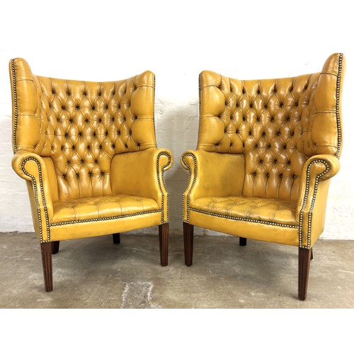 324 - Pair of chesterfield wingback chairs upholstered in mustard yellow leather. 113cm high, 80cm wide.