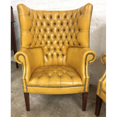 324 - Pair of chesterfield wingback chairs upholstered in mustard yellow leather. 113cm high, 80cm wide.