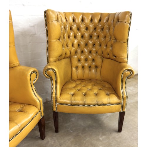 324 - Pair of chesterfield wingback chairs upholstered in mustard yellow leather. 113cm high, 80cm wide.