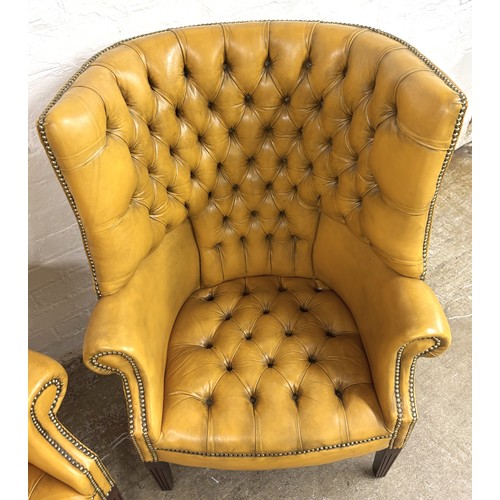 324 - Pair of chesterfield wingback chairs upholstered in mustard yellow leather. 113cm high, 80cm wide.