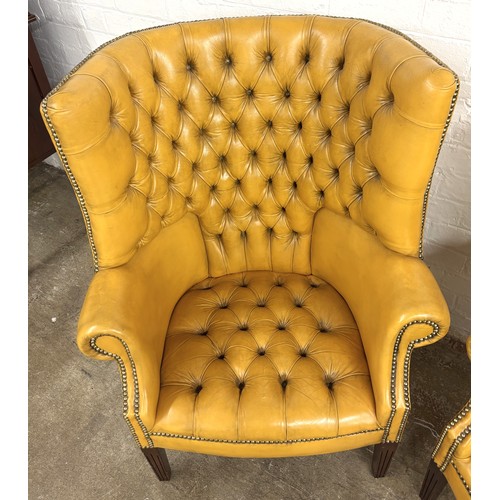324 - Pair of chesterfield wingback chairs upholstered in mustard yellow leather. 113cm high, 80cm wide.