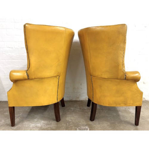 324 - Pair of chesterfield wingback chairs upholstered in mustard yellow leather. 113cm high, 80cm wide.