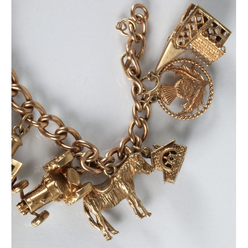 83 - 9ct gold charm bracelet with fourteen assorted gold charms to include cat, bells, clock, tractor, et... 