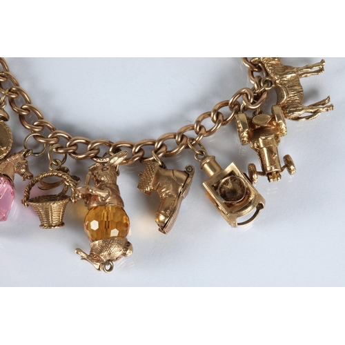 83 - 9ct gold charm bracelet with fourteen assorted gold charms to include cat, bells, clock, tractor, et... 