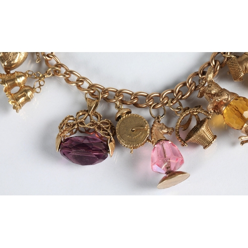 83 - 9ct gold charm bracelet with fourteen assorted gold charms to include cat, bells, clock, tractor, et... 
